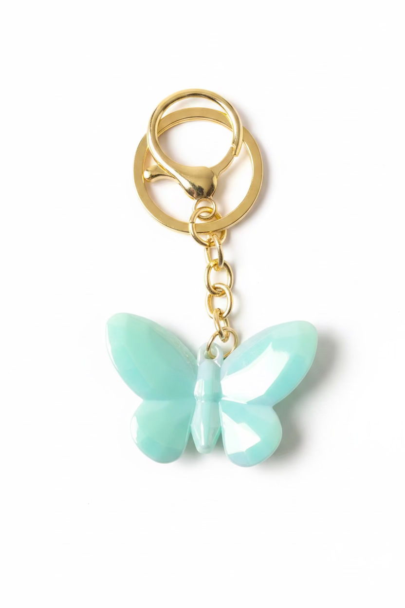 A butterfly-shaped keychain charm in a glossy light aqua or mint green color, attached to a gold-tone metal split ring and short chain, shown on a black textured background.